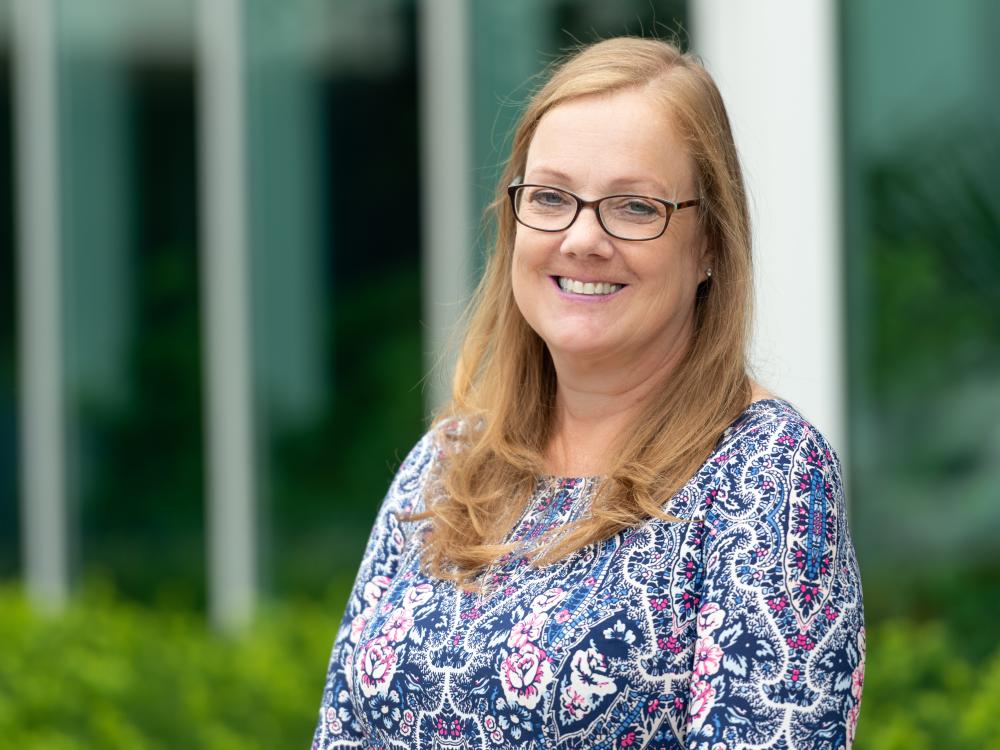 head shot of woman wearing glasses outside office building