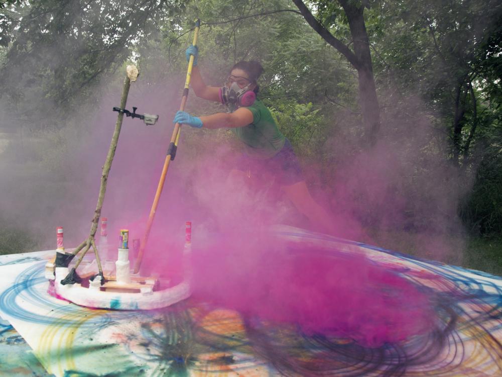 Artist paints in a cloud of pink smoke