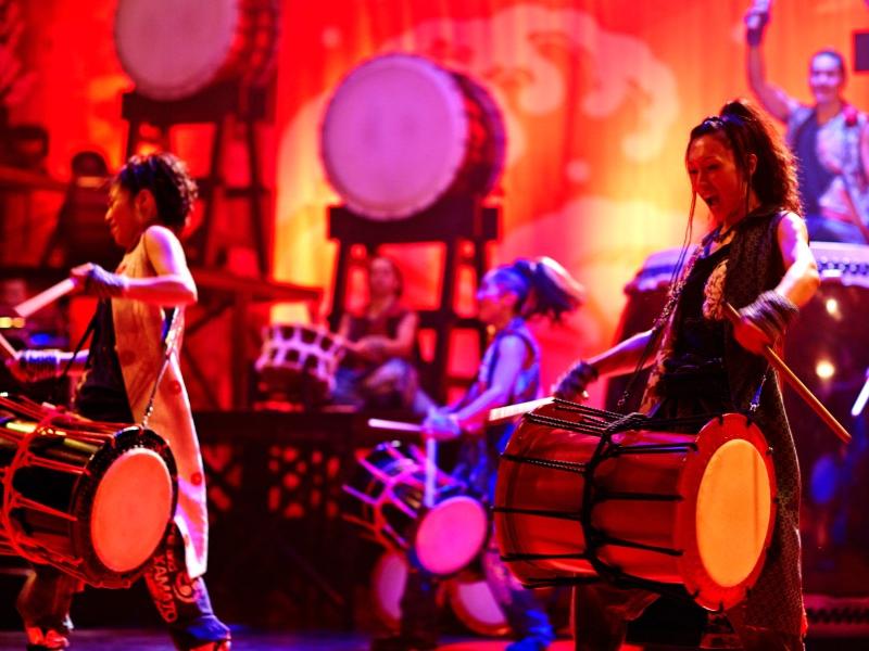 Yamato drummers smile while they pound on their drums.