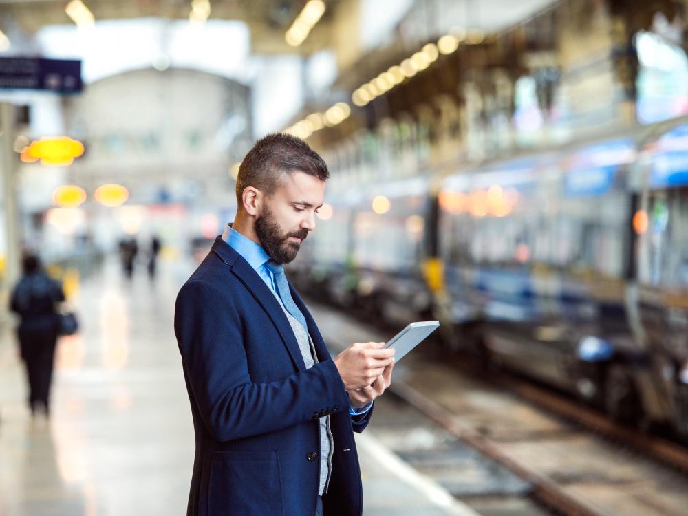 A man checks his smartphone on a subway platform.