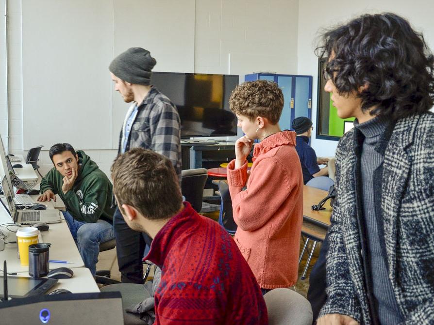 Students sit at computers in class and collaborate on the game