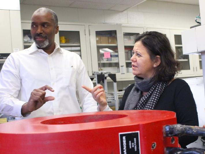 An African American man and an Arab-American woman stand in front of a large magnet.