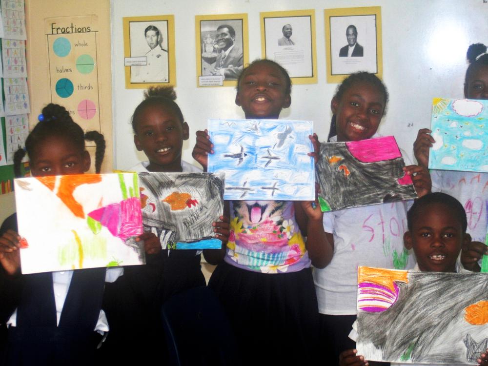 children from San Salvador Island hold up their pieces of an art mural of a coral reef