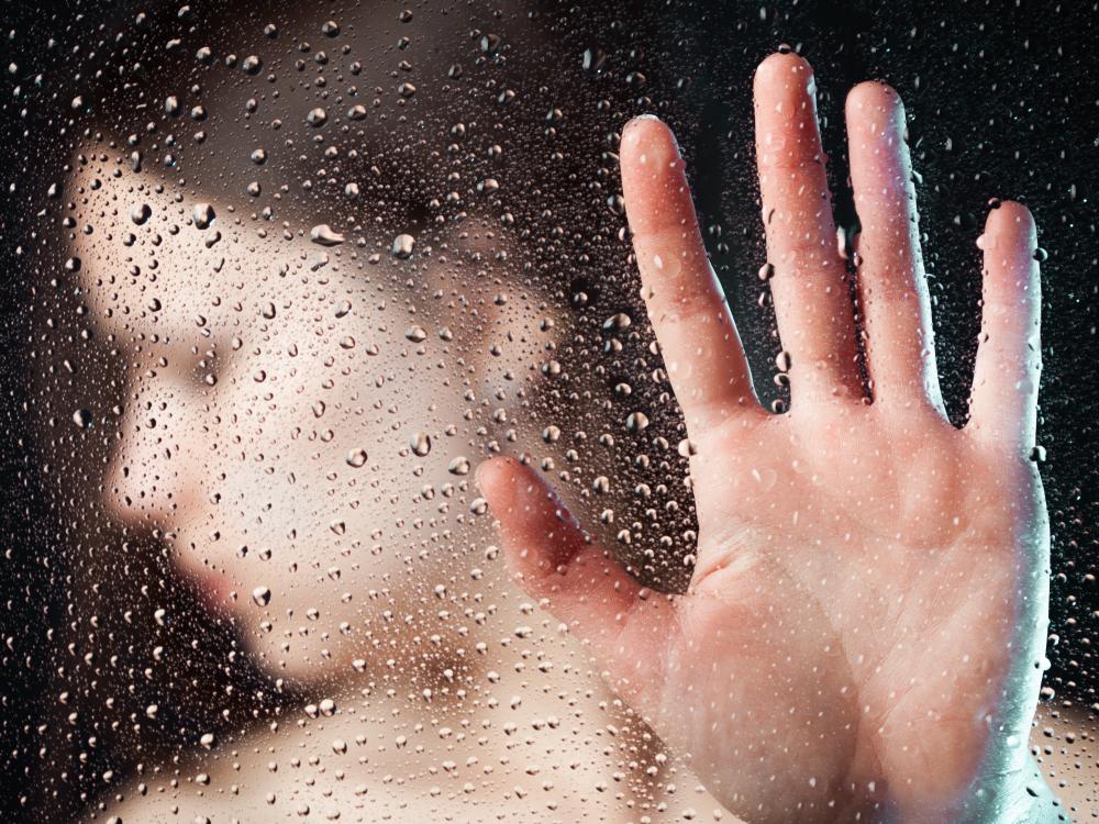 Depressed woman behind glass with her hand up