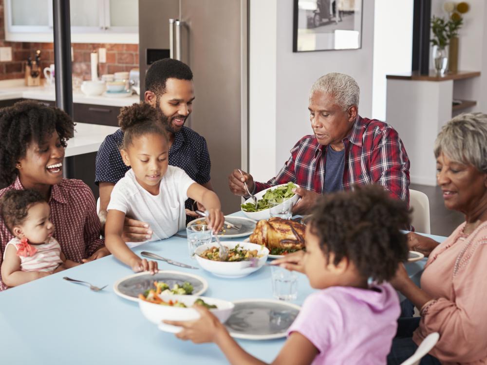 Multi Generation Family Enjoying Meal Around Table At Home