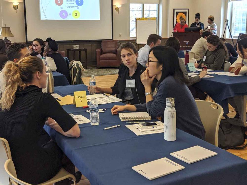 workshop participants at tables discussing an icebreaker activity