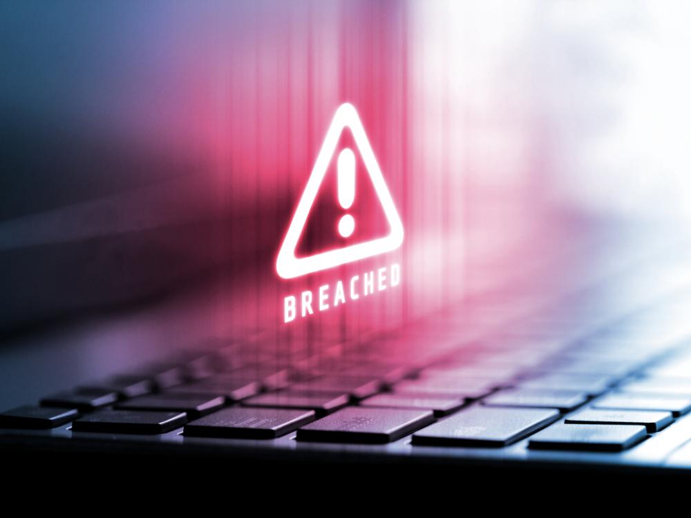 A logo with the word "breached" appears on a laptop screen following a cyber attack