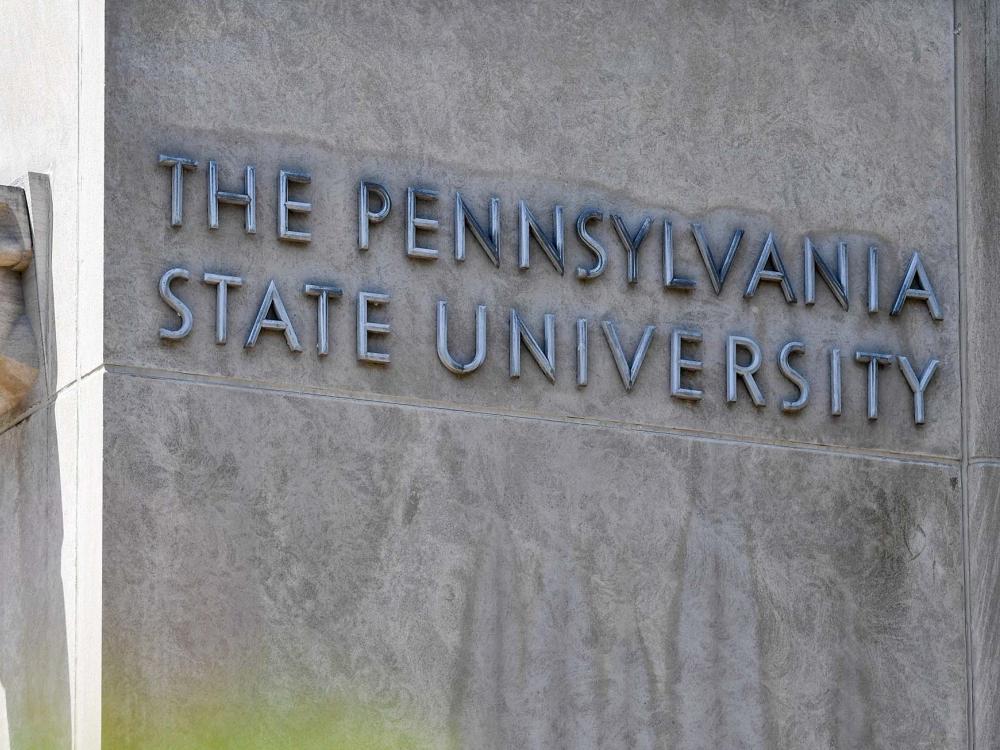 A sign on Pollock Road at the Penn State University Park campus says the name of the university and shows a lion's head.