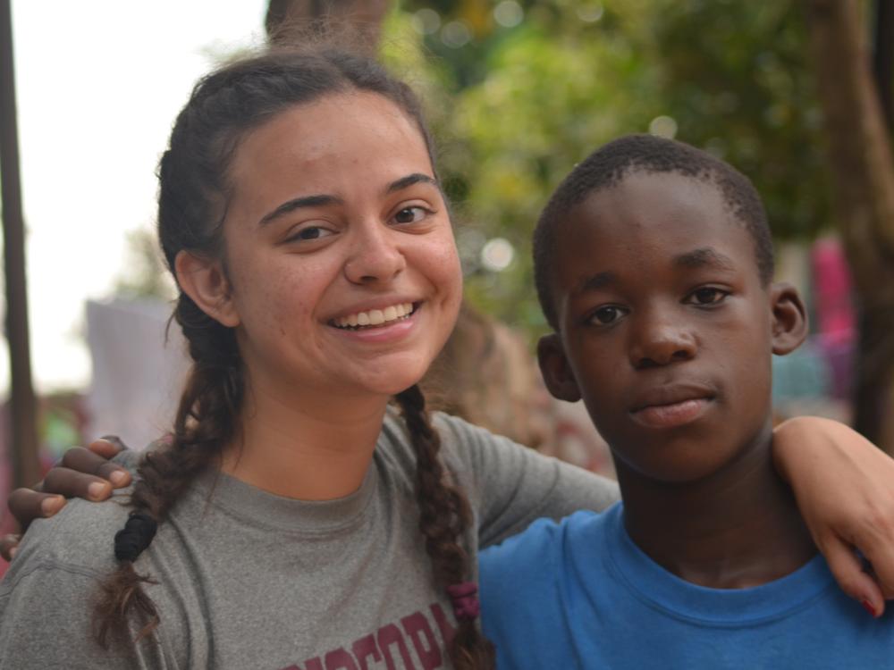 A young woman and teenage boy stand next to each other.