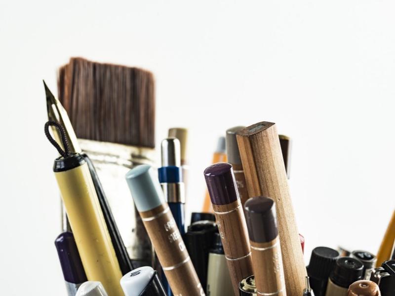 A photo shows paintbrushes, a calligraphy pen and pencils.