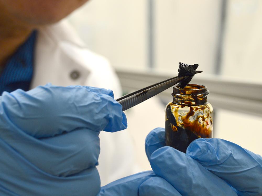 close up shot of hands holding a sample of PetroGel with tweezers
