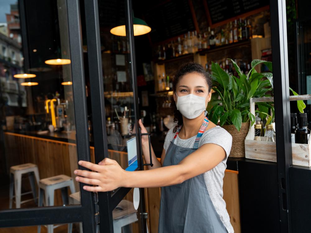 Woman in mask opening a restaurant for business