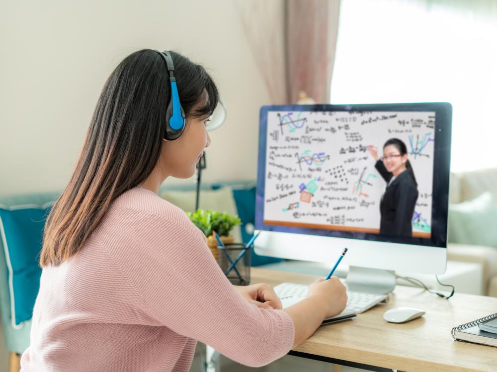 A female student learns virtually from her instructor using a computer screen