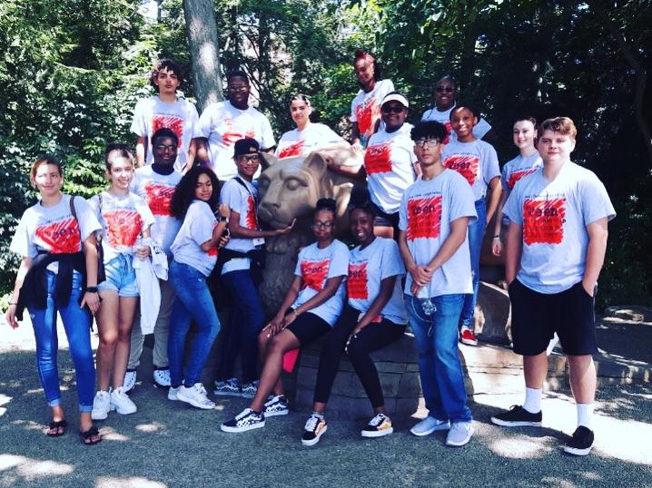 camper standing in matching t-shirts around lion statue