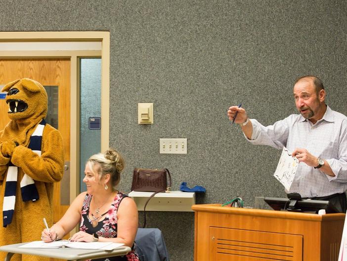 Art auctioneer calls for bids at the 2018 Off the Wall pARTy's art auction as mascot looks on