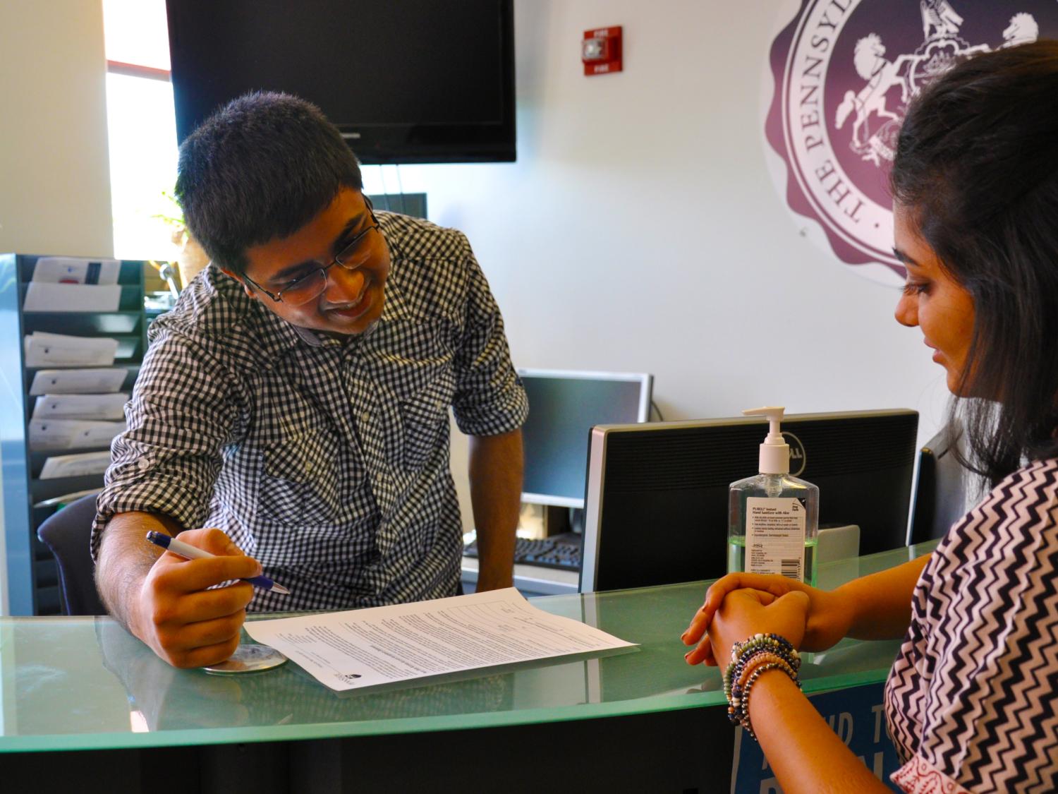 Karan Kalaria helps a college student at a computer station at the IT Service Desk. 