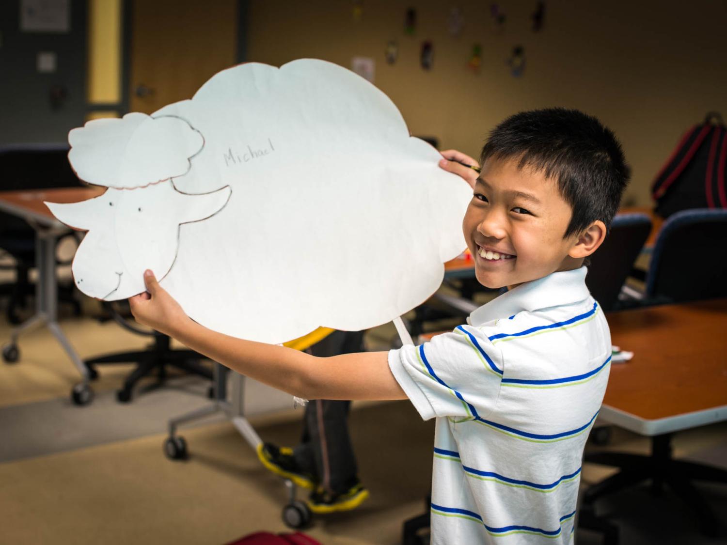 A young boy poses with his art work