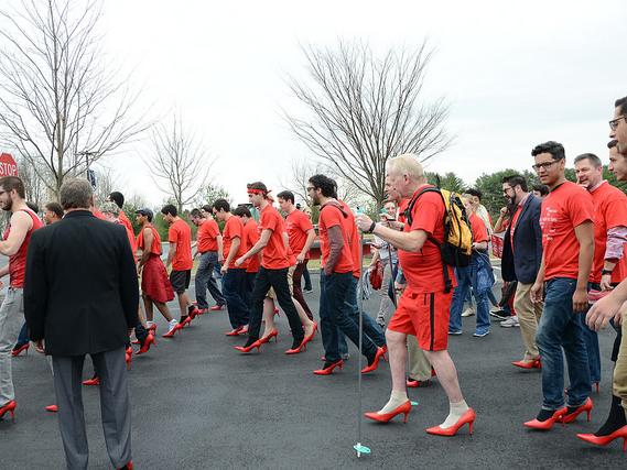 A group mof men in red heels walk for a cause.
