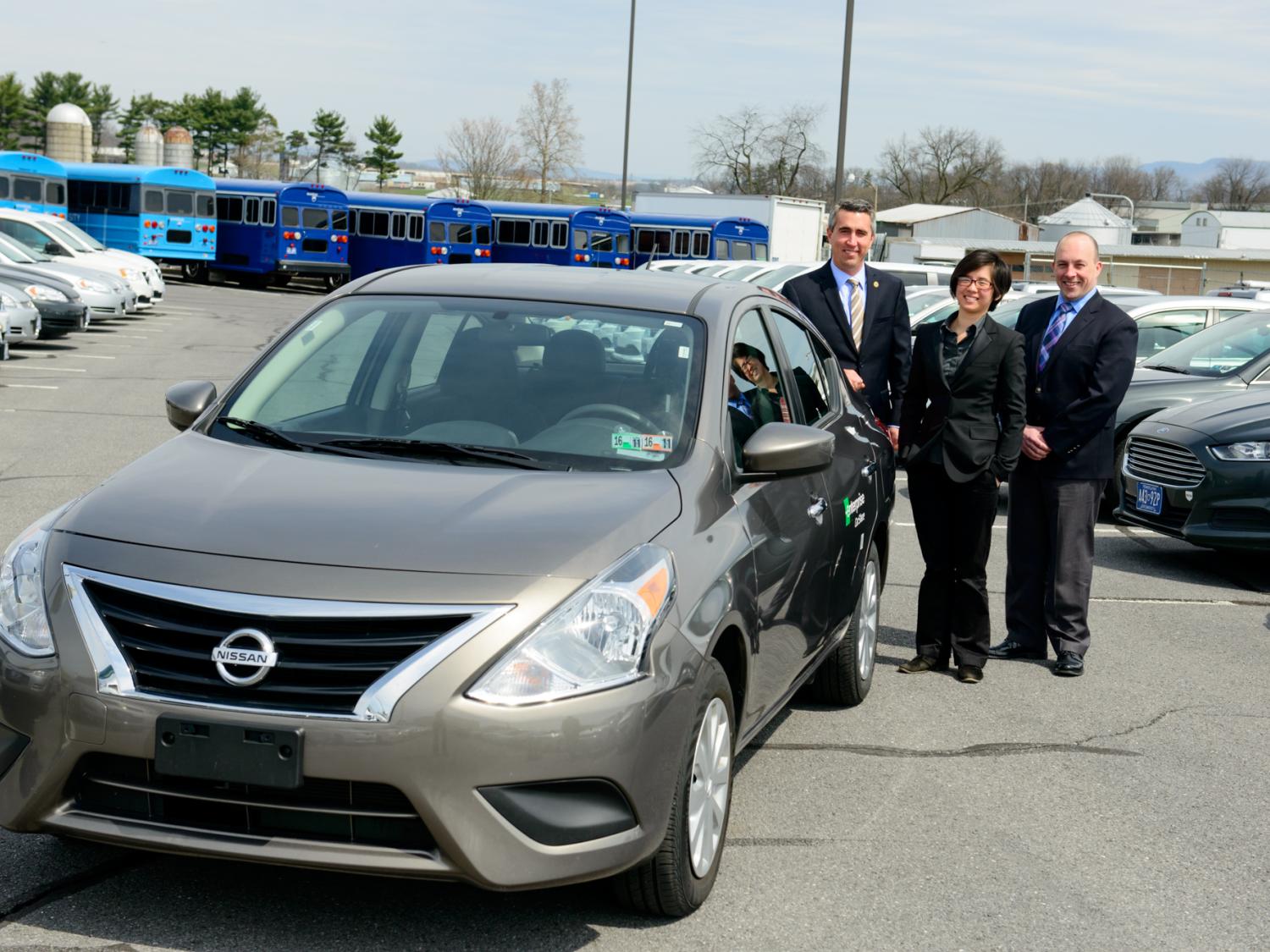 Three people standing by car