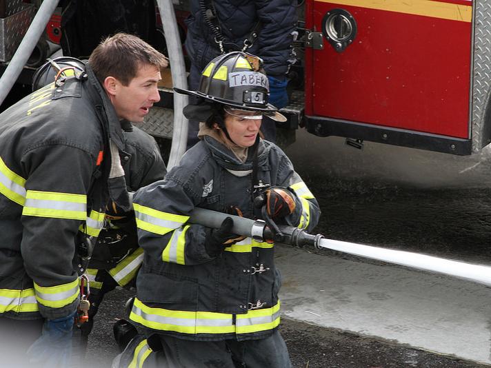 An MBA student gets coaching on using the fire hose. 