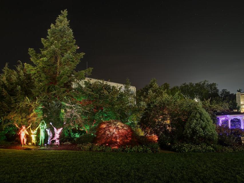 The children statues in Hintz Alumni Garden lit by multiple colors as designed by Stella Murray.