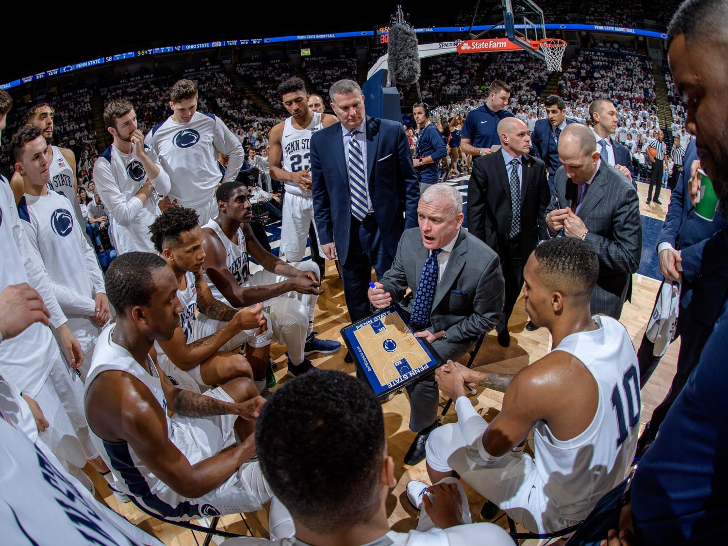Penn State men's basketball team huddled around Coach Patrick Chambers during a timeout