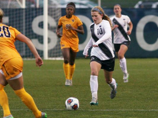 Women's soccer play moves ball against WVU defender