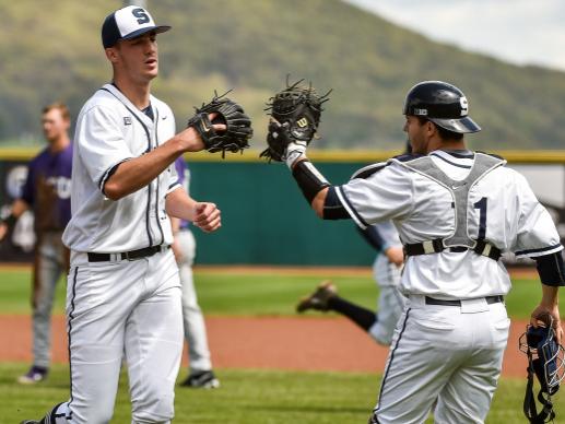 Pitcher and catcher high-five one another