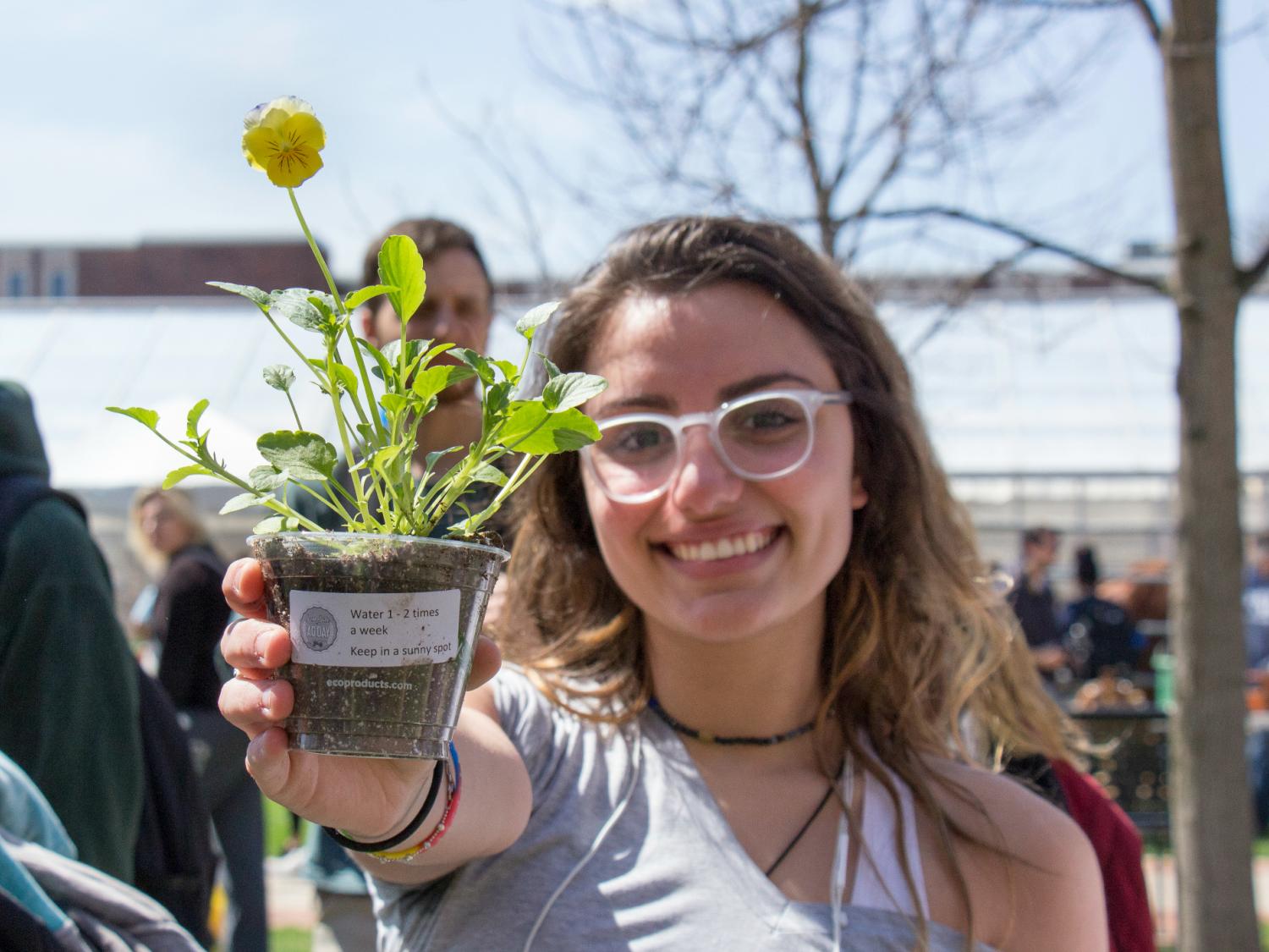Female student holding a pansy planted in a cup