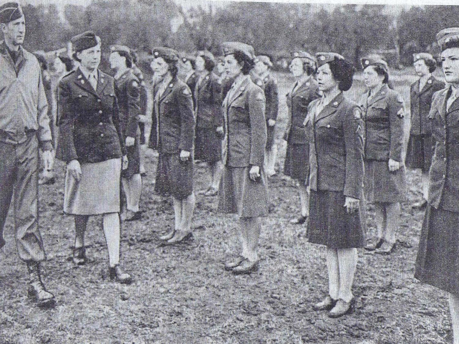 A man and woman in Army uniform inspect a line of women soldiers during WW2