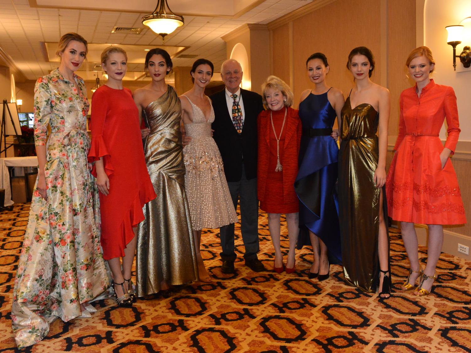 Jeanne and Ed Arnold are at the center of the photo, with four models to their right and three to their left. The group stands in a line posing for a photo.