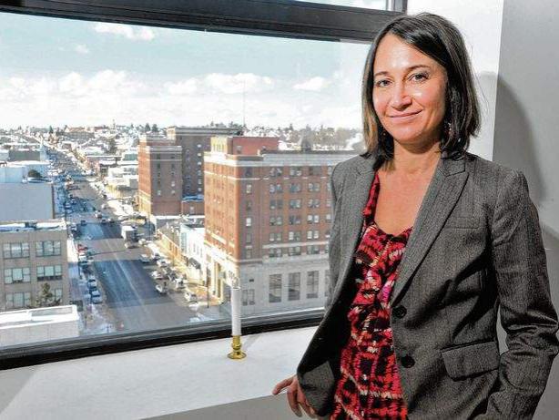 Woman standing next to window that shows city landscape.