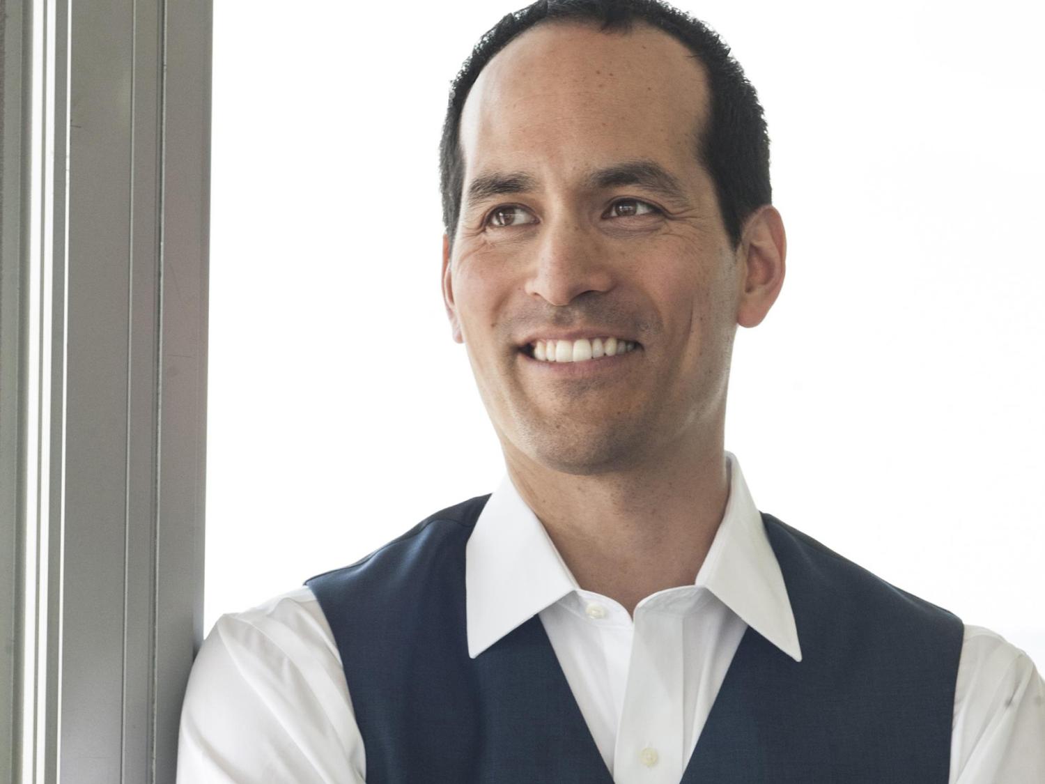 Ian Truitner poses in front of floor-to-ceiling glass windows