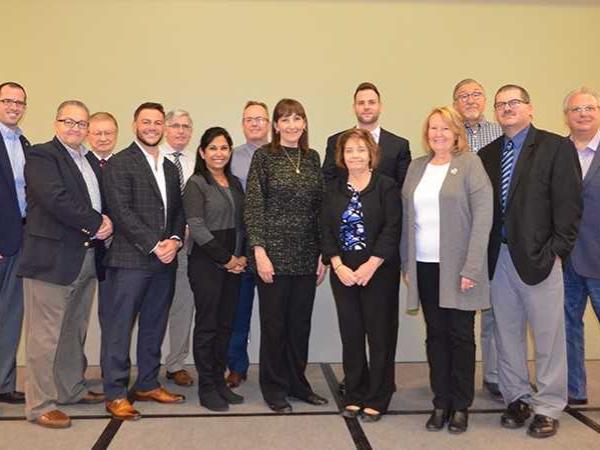 Several men and women from Shenango's advisory board stand together to get their picture taken.
