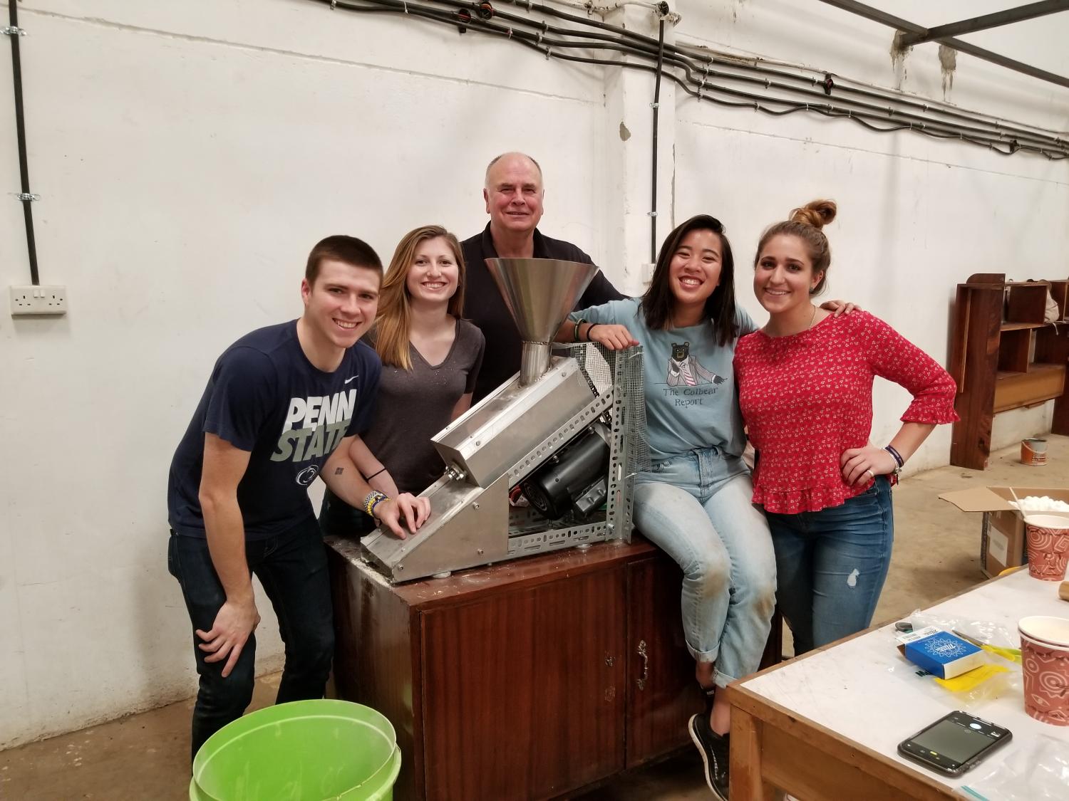 Five people stand around a baobab processing machine