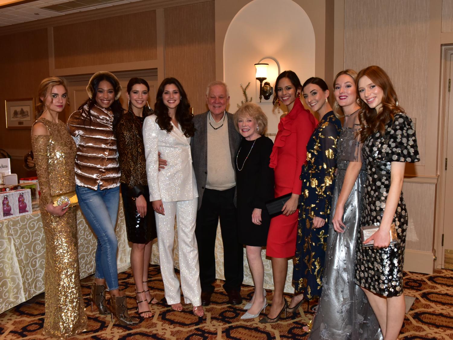 Jeanne and Ed Arnold pose in formal attire, with four female models on each side of them.