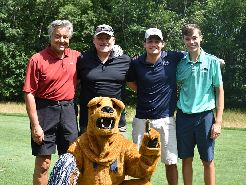 The winning team posing on the green with the Nittany Lion Mascot