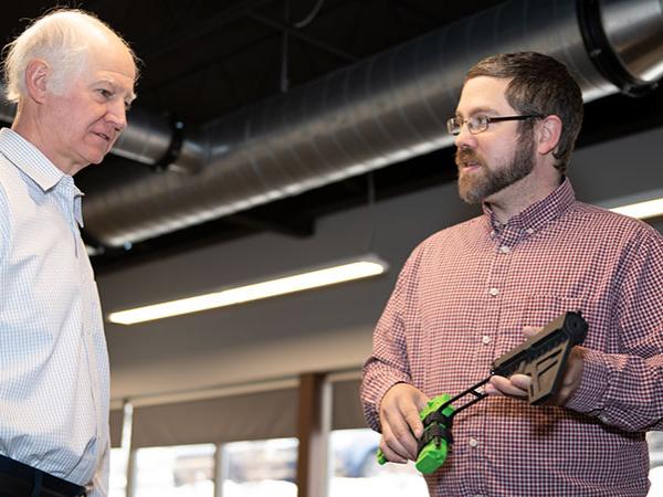 Mark Scaccia looks on as Seth Caton demonstrates use of his original brace for small sidearms.