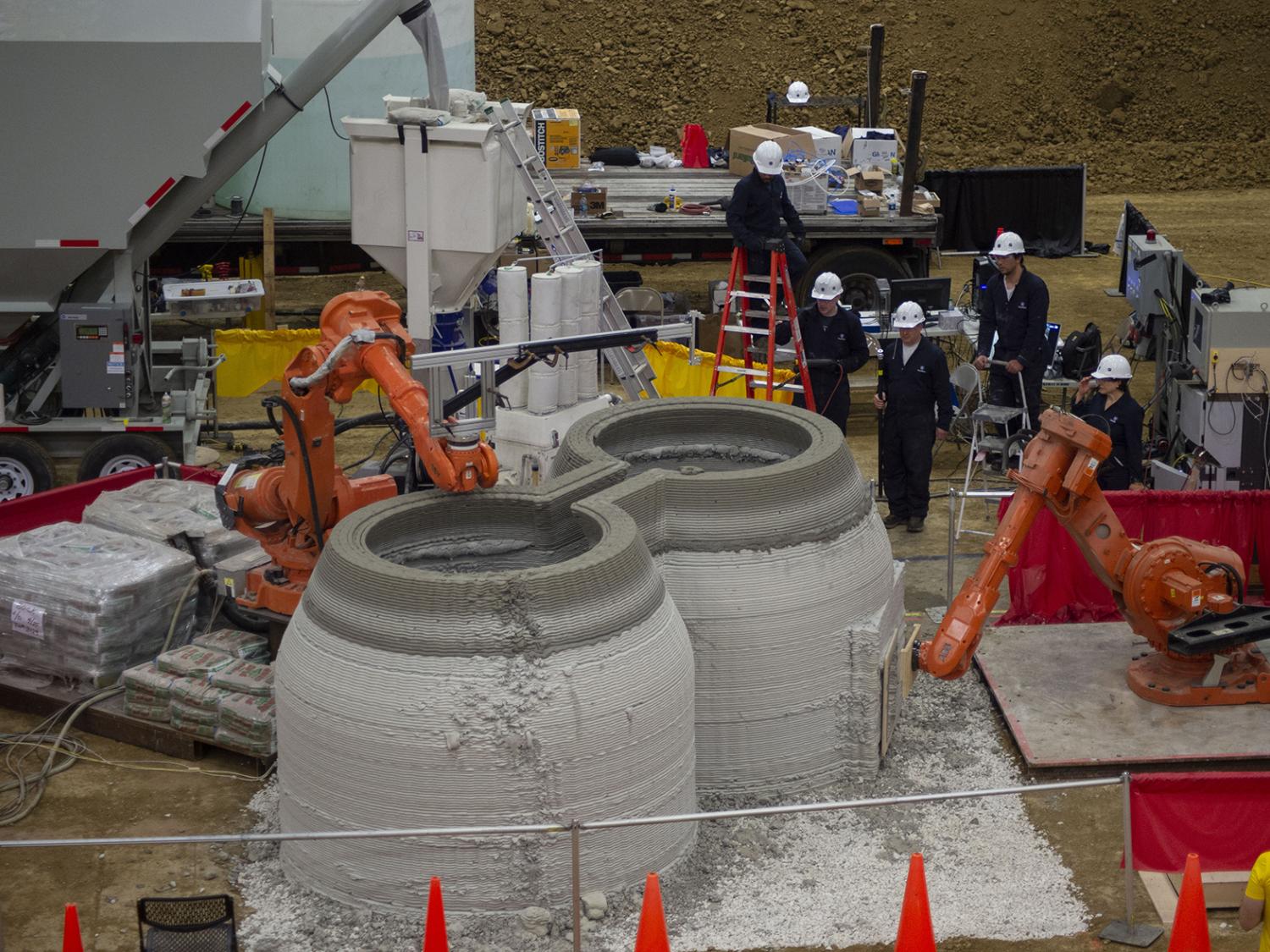 A 3D-printed concrete housing structure as it is being built with Penn State researchers observing the process.