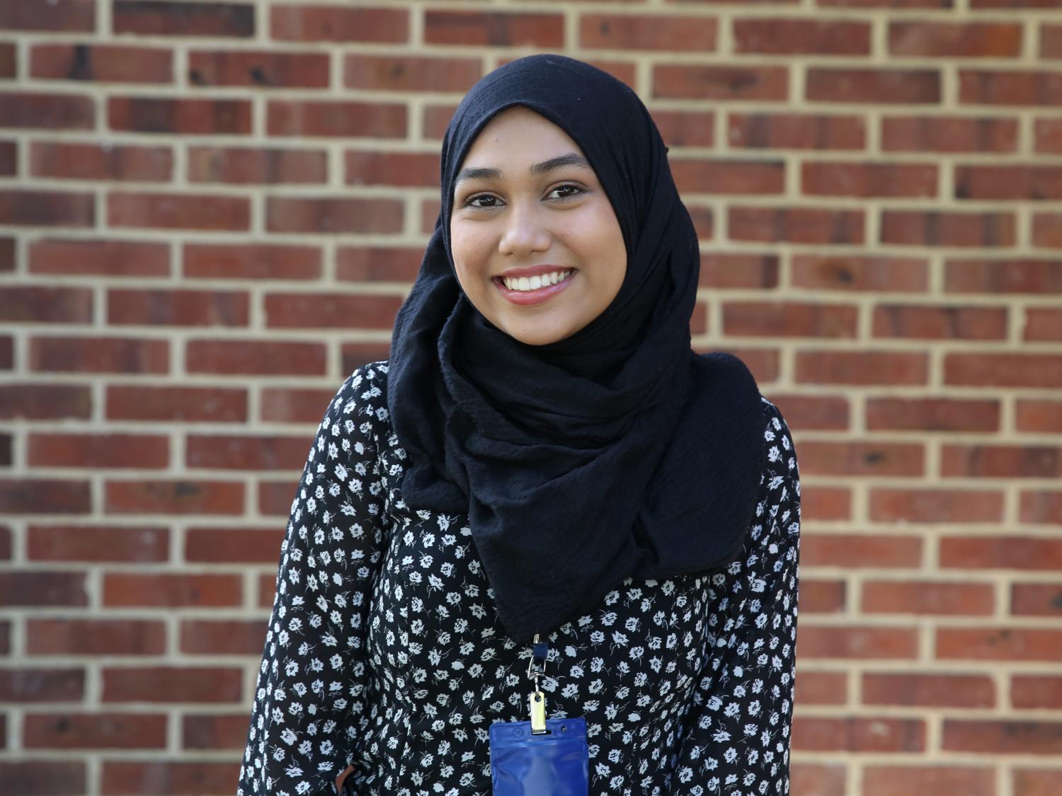 A student standing in front of a brick wall.