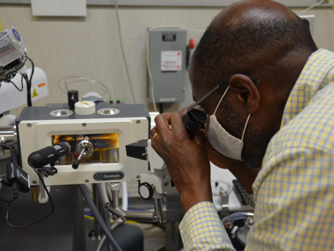 Man peering into a scope at a sample