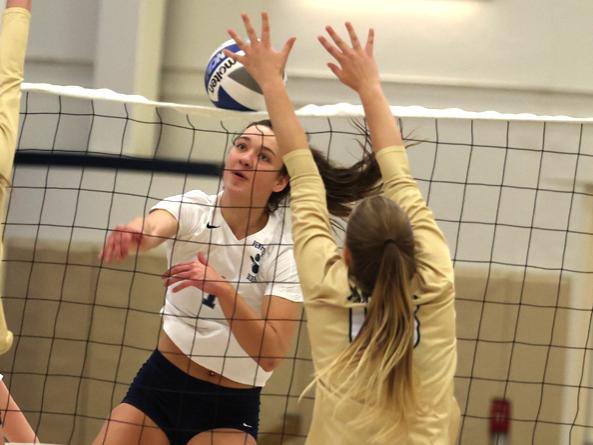 A Penn State Behrend volleyball player spikes the ball.