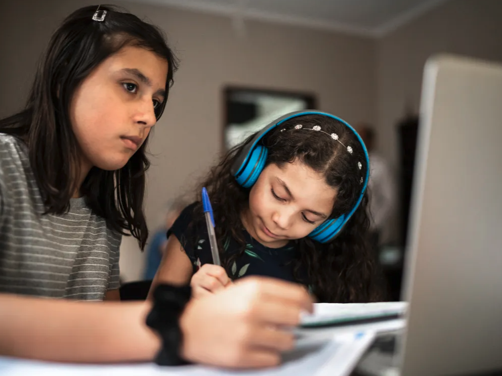 Sisters studying together using laptop on online class at home