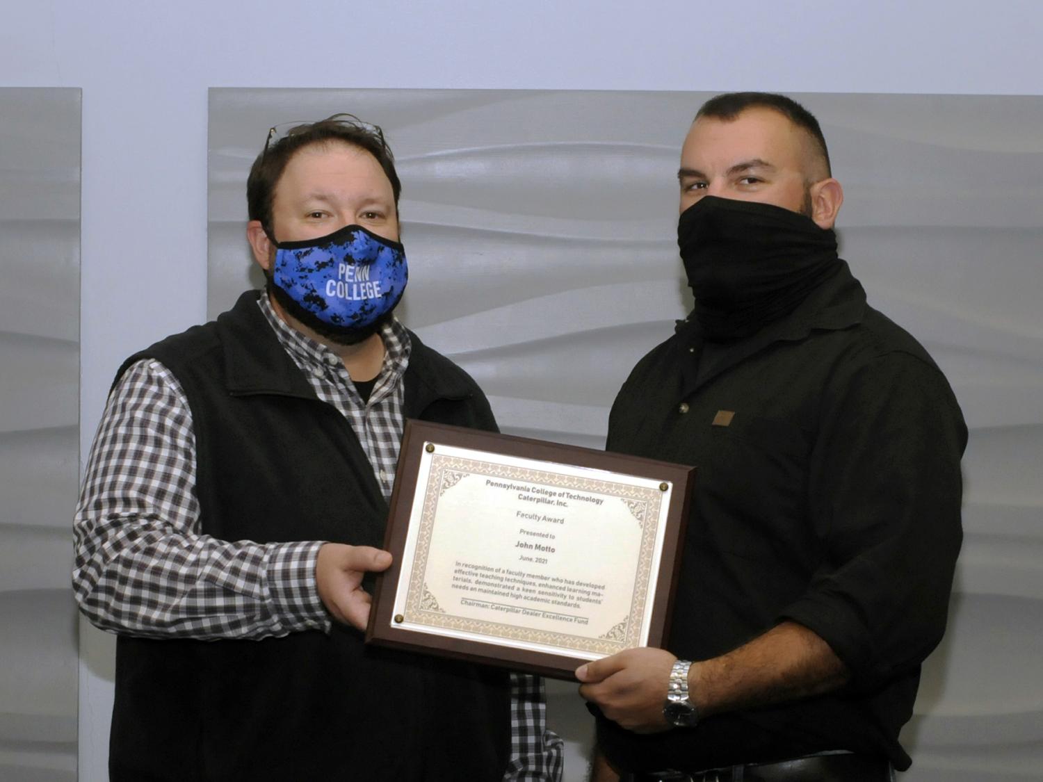 Two people pose for a photo with a certificate displayed between them