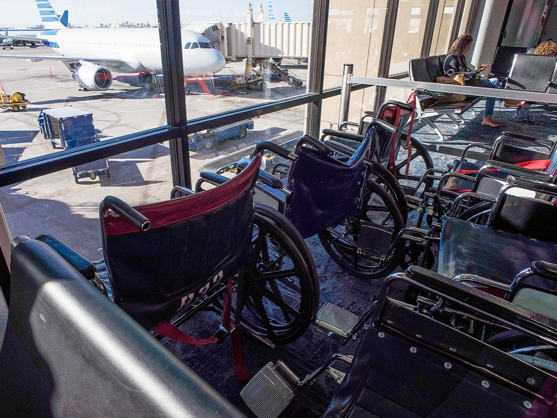 image of wheelchairs sitting in a airport terminal overlooking an airplane 