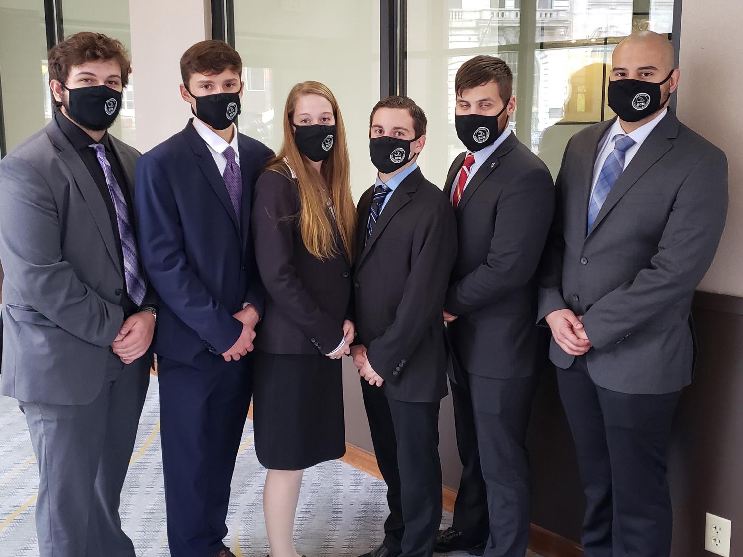 Six people wearing business clothing stand in a row for a photo to be taken