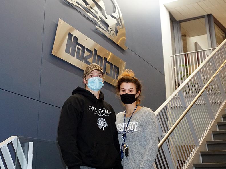 Female student and male student wearing masks and standing side by side on steps.