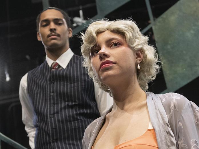 woman in foreground with blonde hair looking sad with a man in the background