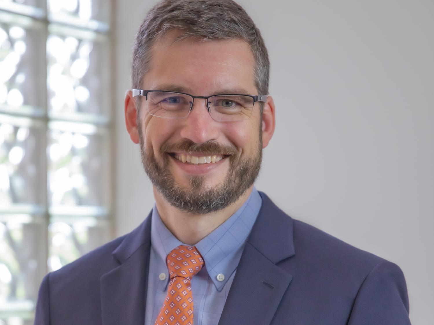 Man smiles in suit for headshot photo