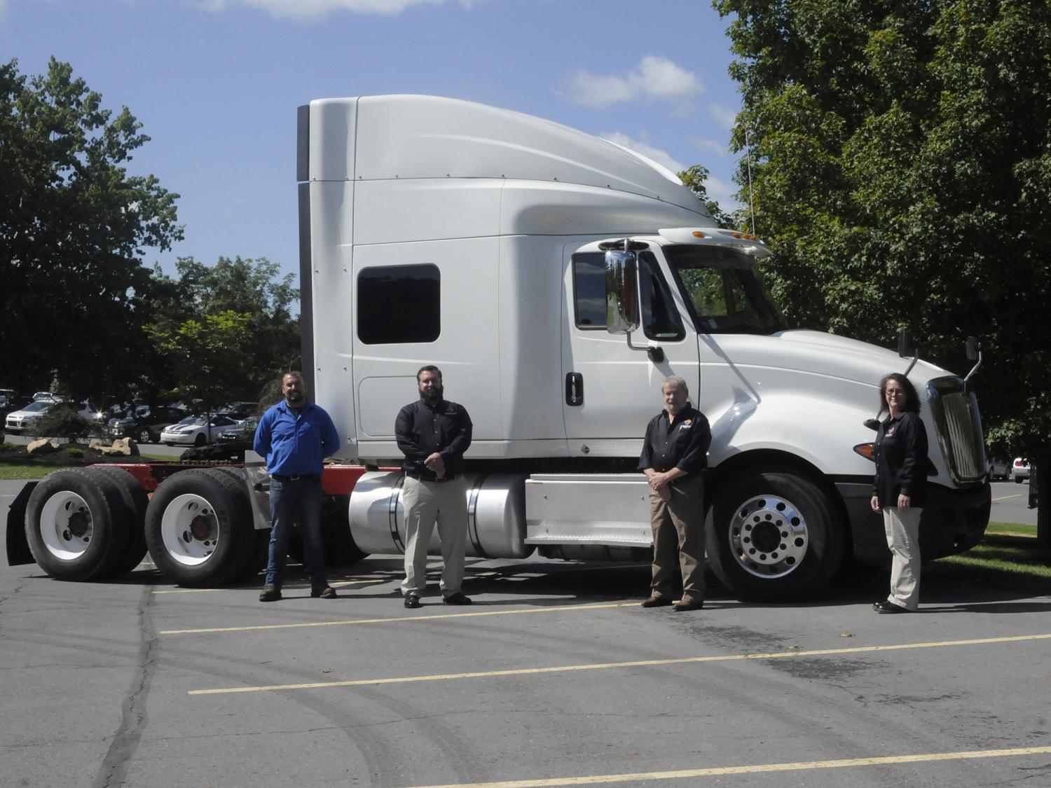 Four people standing in front of a truck